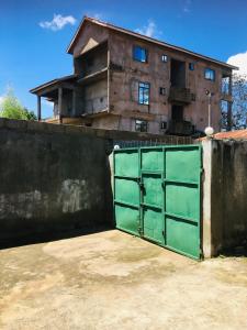 a house with a green gate in front of a wall at Arusha homestay in Arusha