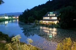 a house sitting on the side of a river at night at Penzion Benatky in Piešťany
