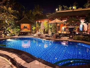 a large blue swimming pool in front of a house at Mikuk Cottages Canggu in Canggu