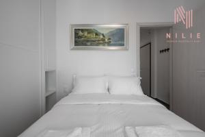 ein weißes Bett in einem weißen Schlafzimmer mit einem Bild an der Wand in der Unterkunft Lusso Bianco, Nilie Hospitality MGMT in Thessaloniki