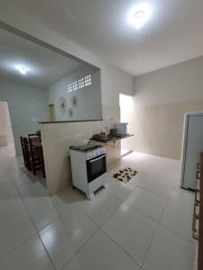 a white kitchen with a stove and a sink at Casa 2/4 para temporada in Aracaju