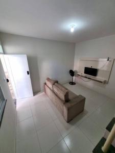 a living room with a couch and a television at Casa 2/4 para temporada in Aracaju