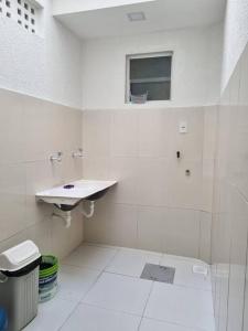 uma casa de banho branca com um lavatório e uma janela em Casa 2/4 para temporada em Aracaju