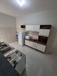 a kitchen with white cabinets and a stove and refrigerator at Casa 2/4 para temporada in Aracaju