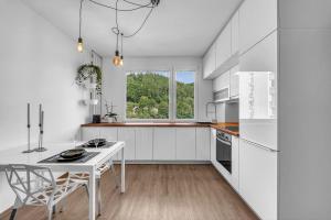 - une cuisine avec des placards blancs, une table et des chaises dans l'établissement Apartmán Malina, à Svoboda nad Úpou