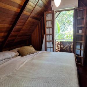 ein Schlafzimmer mit einem Bett in einem Zimmer mit einem Fenster in der Unterkunft Chalé de Madeira nr03 - Exuberante Flora e Fauna - IMBASSAI in Mata de Sao Joao