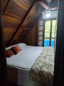- un grand lit dans une chambre avec plafond dans l'établissement Chalé de Madeira nr03 - Exuberante Flora e Fauna - IMBASSAI, à Mata de São João