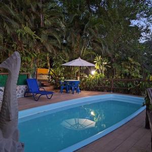 einen Pool mit einem Tisch, Stühlen und einem Sonnenschirm in der Unterkunft Chalé de Madeira nr03 - Exuberante Flora e Fauna - IMBASSAI in Mata de Sao Joao