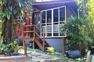 une petite maison avec un escalier menant à une terrasse couverte dans l'établissement Chalé de Madeira nr03 - Exuberante Flora e Fauna - IMBASSAI, à Mata de São João