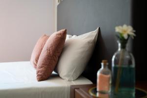 two pillows on a bed with a vase of flowers at Hotel Onix in Viseu