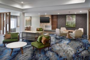 vestíbulo con sillas, mesas y TV en Fairfield Inn & Suites Atlanta McDonough, en McDonough