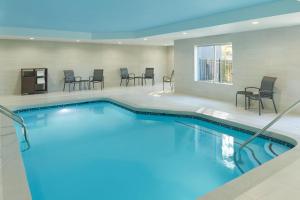 una piscina en una habitación de hotel con sillas y mesa en Fairfield Inn & Suites Atlanta McDonough en McDonough
