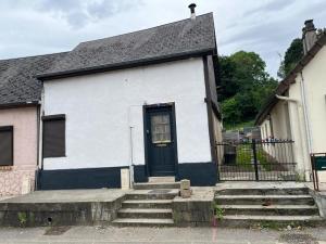 a white house with a black door and stairs at DUPLEX REFAIT NEUF à MONCHAUX SORENG in Monchaux-Soreng