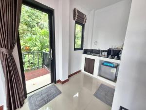 a room with a kitchen with a window and a balcony at Lanta noblesse in Ko Lanta