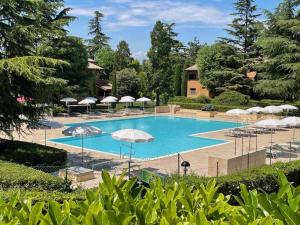 uma grande piscina azul com guarda-sóis e árvores em Casa Vittoria Sirmione Punta Grò con Piscina em Sirmione
