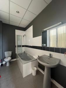 La salle de bains est pourvue d'une baignoire, d'un lavabo et de toilettes. dans l'établissement Hôtel Le Phare, à Ouistreham