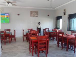 a woman standing in a dining room with red tables and chairs at Belmont Villas Mbale in Mbale
