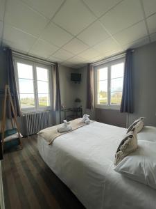 a bedroom with a large white bed with windows at Hôtel Le Phare in Ouistreham