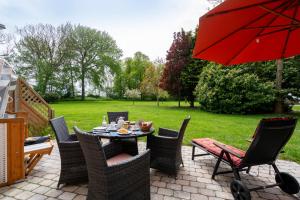 eine Terrasse mit einem Tisch und Stühlen mit einem roten Regenschirm in der Unterkunft Fehmarn Mein Urlaub in Fehmarn