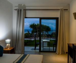 a bedroom with a sliding glass door with a view of the ocean at Le Marin, Rodrigues Island in Rodrigues Island