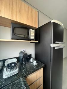 a kitchen with a black refrigerator and a microwave at SoHo Bosque - Studios & Lofts in Presidente Prudente