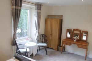 a bedroom with a desk and a table and a mirror at Birch Tree House in Windermere