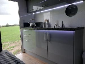 a kitchen with white cabinets and a sink and a window at Military Shepherd Hut in Haxey