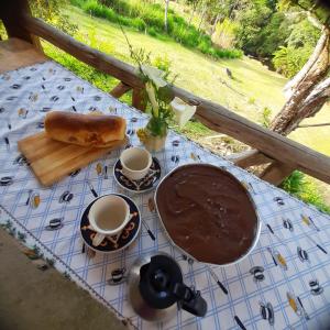 een tafel met twee kopjes koffie en een chocoladetaart bij Rancho Pedra do Picú in Itamonte