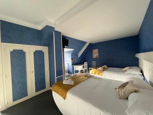 2 camas en una habitación con paredes azules en Hôtel Le Phare en Ouistreham