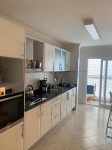 a kitchen with white cabinets and black counter tops at Laginha Beachview in Mindelo