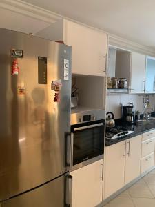 a kitchen with a stainless steel refrigerator and white cabinets at Laginha Beachview in Mindelo