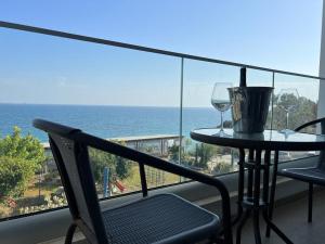 balcón con mesa y 2 copas de vino en Governors Beach Panayiotis, en Playa del Gobernador