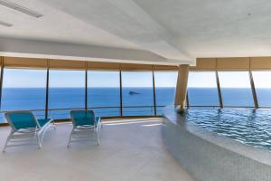 una piscina en un edificio con sillas y el océano en Intempo Residential Sky Resort & Spa - Benidorm, España, en Benidorm