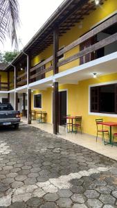 un edificio con mesas y sillas delante de él en Casa da Si Suítes & Hostel, en Ubatuba