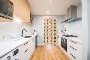 uma cozinha com armários brancos e piso em madeira em 37 Galaxy A em Lake Tekapo