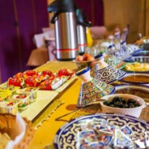 a long table with plates of food on it at Merzouga Desert Campsite &Activities in Merzouga +35 photos