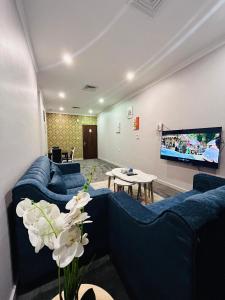 科威特的住宿－De Iris Regency Fahaheel，客厅配有蓝色的沙发和平面电视。