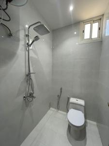 a white bathroom with a toilet and a shower at شقق الايام المضيئة المخدومة in Najran
