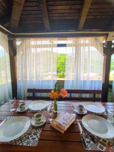 a wooden table with plates and a vase of flowers on it at Apartman Bilanovic in Konjic