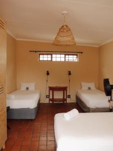 a room with two beds and a table in it at Villa Viva Cape Town in Cape Town