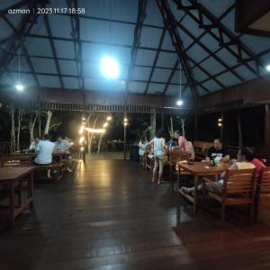 un grupo de personas sentadas en mesas en un restaurante en Maratua Dive Center And Lodge, en Maratua Atoll