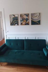 un sofá verde en una sala de estar con pinturas en la pared en Parisien style T2 in center of Puteaux, en Puteaux