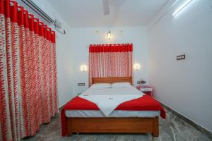 a bedroom with a bed with red drapes at BIJIS HOMESTAY in Alleppey