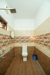a bathroom with a toilet in a room with wooden floors at BIJIS HOMESTAY in Alleppey