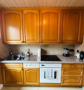a kitchen with wooden cabinets and a stove top oven at B17 Two Bed Apartment West Town in Heidenheim an der Brenz