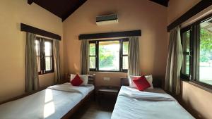 two beds in a room with two windows at Lumbini Buddha Garden Resort in Lumbini
