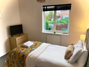 a bedroom with a bed and a television and a window at Charming Home in Wellingborough in Wellingborough