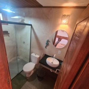 a bathroom with a toilet and a sink and a mirror at Casa Aeolus in Camocim