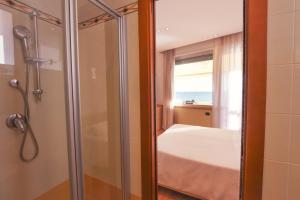 a bathroom with a shower and a bed with a window at Hotel Florida Lerici in Lerici