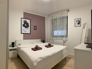 a bedroom with a white bed with two brown pillows on it at Apartman Santosha in Čakovec